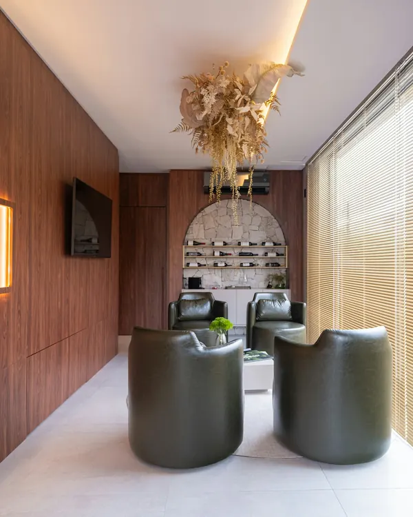 A waiting lounge with walnut walls, green leather armchairs and a stone arch
