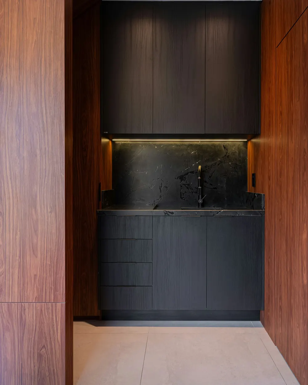 The staff pantry with dark cabinetry and a black marble top