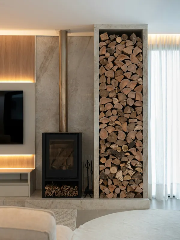 A black wood stove beside a stone-clad log store with warm hidden lighting
